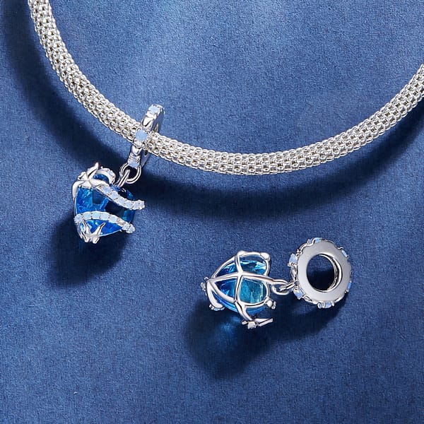 Buzzworthy Beauties: 10 Must-Have Bug-Inspired Jewelry Pieces of 2023 18 Cinderella Magic Glass Heart Dangle Charm crafted from s925 sterling silver, featuring a blue glass heart wrapped in opal-adorned silver swirls with butterfly accents.